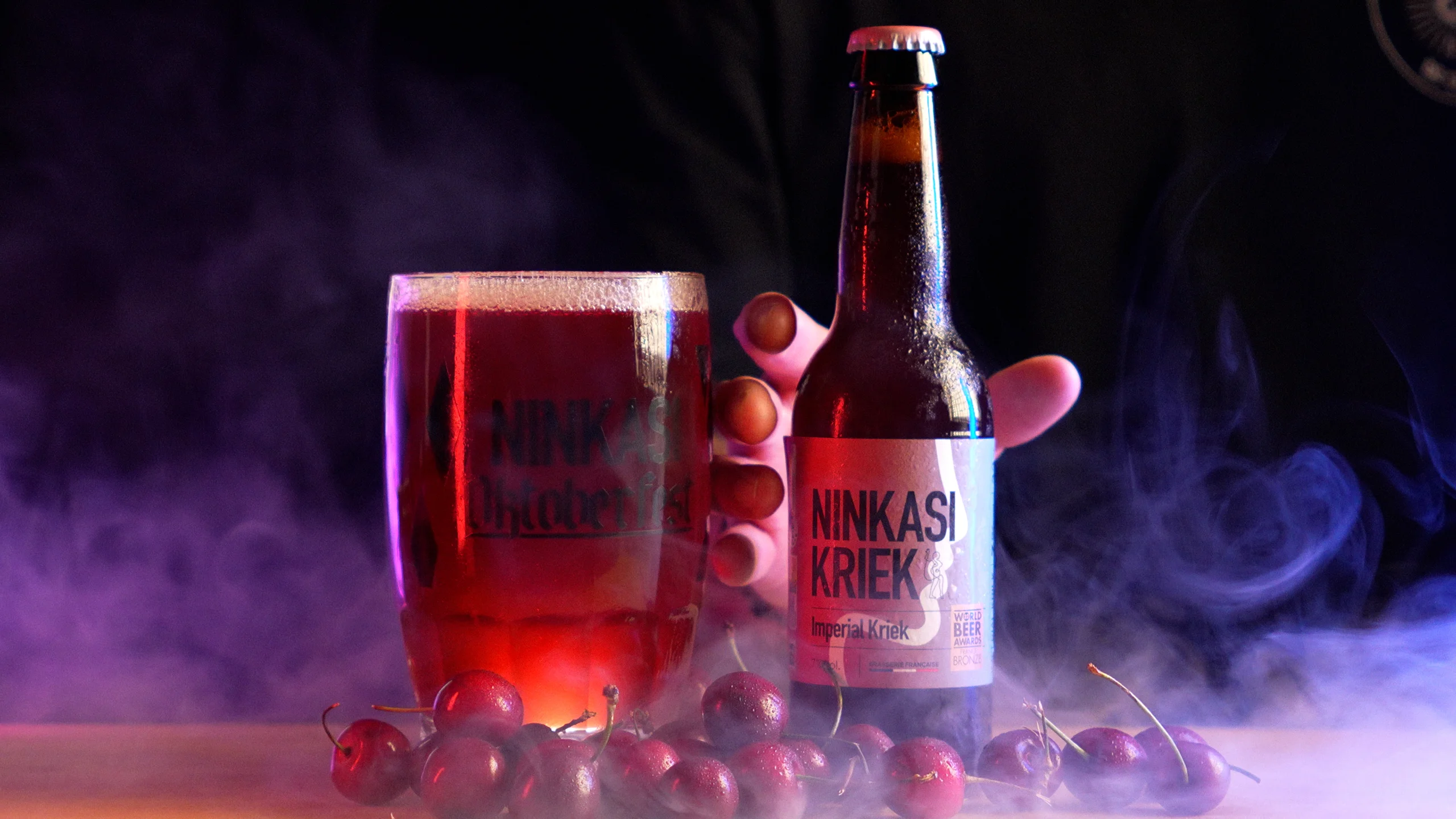 Bouteille de Ninkasi Kriek Imperial et chope de bière à la cerise entourées de cerises, ambiance fumée violette